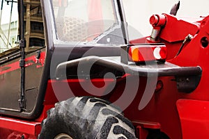 A red forklift truck stands on a rough terrain in the yard