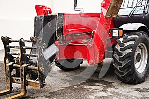 A red forklift truck stands on a rough terrain in the yard