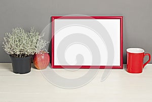 Red frame mockup with plant pot, mug and apple on wooden shelf