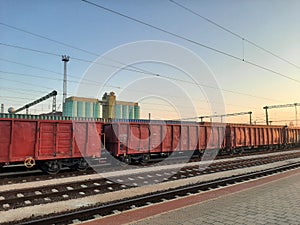 Red freight train wagons on train station in sunset