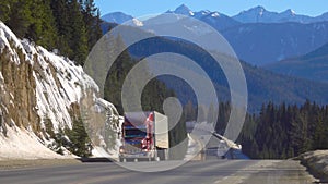 Red freight truck hauls a container across the beautiful Jasper National Park.