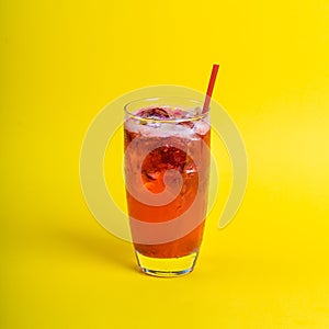 red fresh cocktail smoothie jusice in glass with ice on yellow background. vitamin drink detox