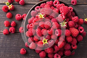 Red fresh raspberries on brown rustic wood background