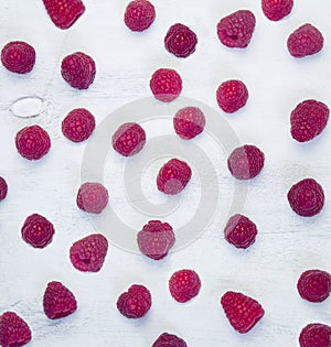 Red fresh raspberries on white rustic wood background