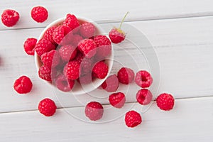 Red fresh raspberries on white rustic wood background