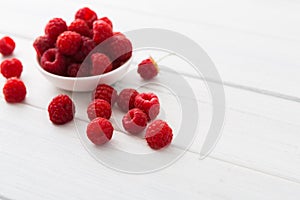 Red fresh raspberries on white rustic wood background