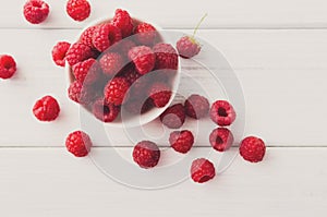 Red fresh raspberries on white rustic wood background