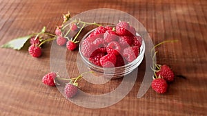 Red fresh ripe eco bio raspberries fruit in the glass and brunches with berries on wooden background.