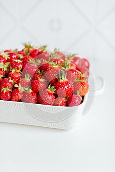 Red fresh strawberries from bio fields on a white dish in the kitchen