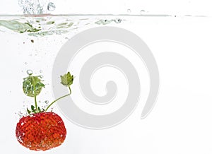 Red fresh strawberries thrown into the water, under water. Spat and splash