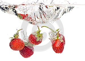 Red fresh strawberries thrown into the water, under water. Spat and splash