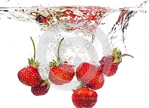 Red fresh strawberries thrown into the water, under water. Spat and splash