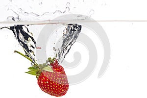 Red fresh strawberries thrown into the water, under water. Spat and splash