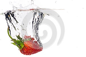 Red fresh strawberries thrown into the water, under water. Spat and splash