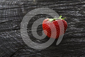 Red fresh strawberry on black rustic wood background
