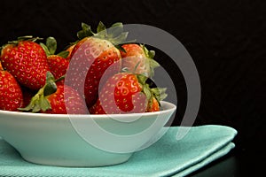 Red fresh strawberry in a bowl on black background