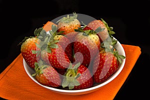 Red fresh strawberry in a bowl on black background