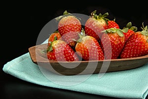 Red fresh strawberry in a bowl on black background