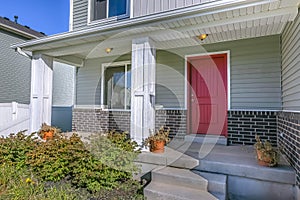 Red front door of a home with porch and stairs