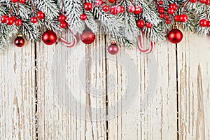 Red frozen holly berries, baubles and green fir branch on white wooden background card. Christmas border. Minimal Xmas flat lay