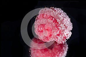 red frozen raspberry against black background