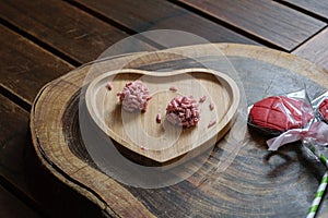 Red fruit brigadiers on a wooden board, next to strawberry lollipops photo