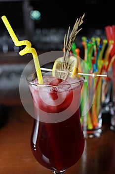 Red fruity alcoholic cocktail with straw and garnish.