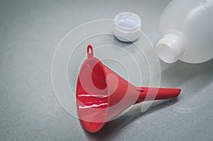 Red funnel and plastic bottle. Selective focus, copy space