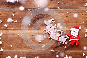 Santa claus riding Christmas sledge with deers on brown wooden background, xmas present gift sale, top view, copy space