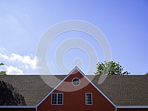 Red gable roof of big house covered with white wooden framed.