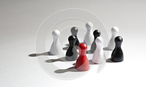 Red game piece among black and white ones on grey background. Career promotion concept
