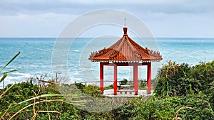 Red gazebo stands on a hill overlooking the ocean in Jinshan