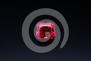 A red gemstone sits on a black surface