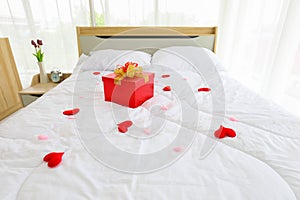 Red gift box as a present on the bed for surprise your partner in newly wed marriage couple for valentines day and love concept pu