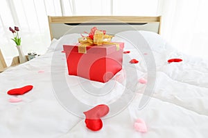 Red gift box as a present on the bed for surprise your partner in newly wed marriage couple for valentines day and love concept wi photo