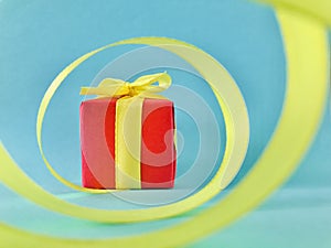 Red Gift box at the end of the spiral yellow ribbon, teal background.