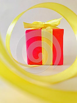 Red Gift box at the end of the spiral yellow ribbon with white background, vertical.