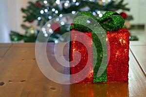 Red gift box with green lace and christmas tree with christmas lights