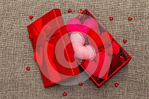 Red gift box with handmade felt hearts on a woven background