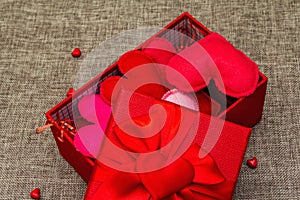 Red gift box with handmade felt hearts on a woven background