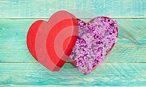 Red gift box with lilac flowers on wooden background