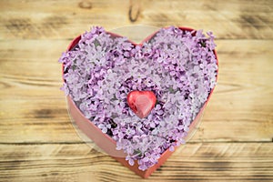 Red gift box with lilac flowers on wooden background