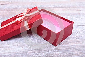 Red gift box with ribbon bow opened on vintage white wooden table