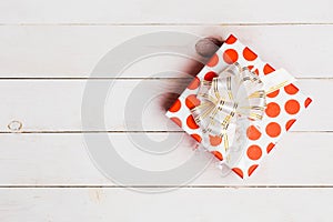 Red gift box with ribbon on white wooden background with copy space, top view