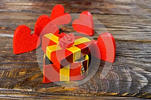 Red gift box in the shape of a heart ajar, and from it hangs a pendant in the shape of a wooden Shoe with briliant it stands on a