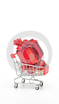Red gift box in a shopping cart on a white background