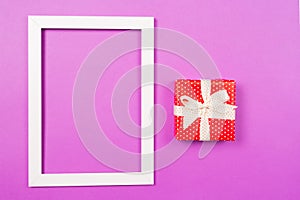 Red Gift box and white picture frame on purple background. St Valentine`s Day Mothers`s Day Wedding Birthday concept