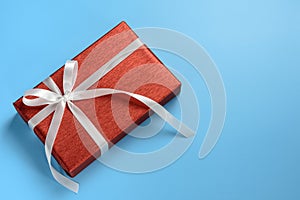Red gift box with white ribbon on blue background