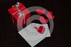 A red gift box with a white ribbon and bow, and an envelope full of hearts.