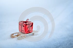 Red gift box on wooden sled in winter in snow, christmas gifts delivery background